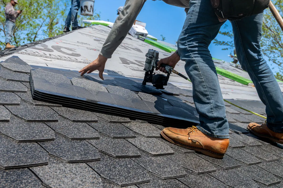 Roofer nailing asphalt shingles on a residential roof in Los Angeles, CA