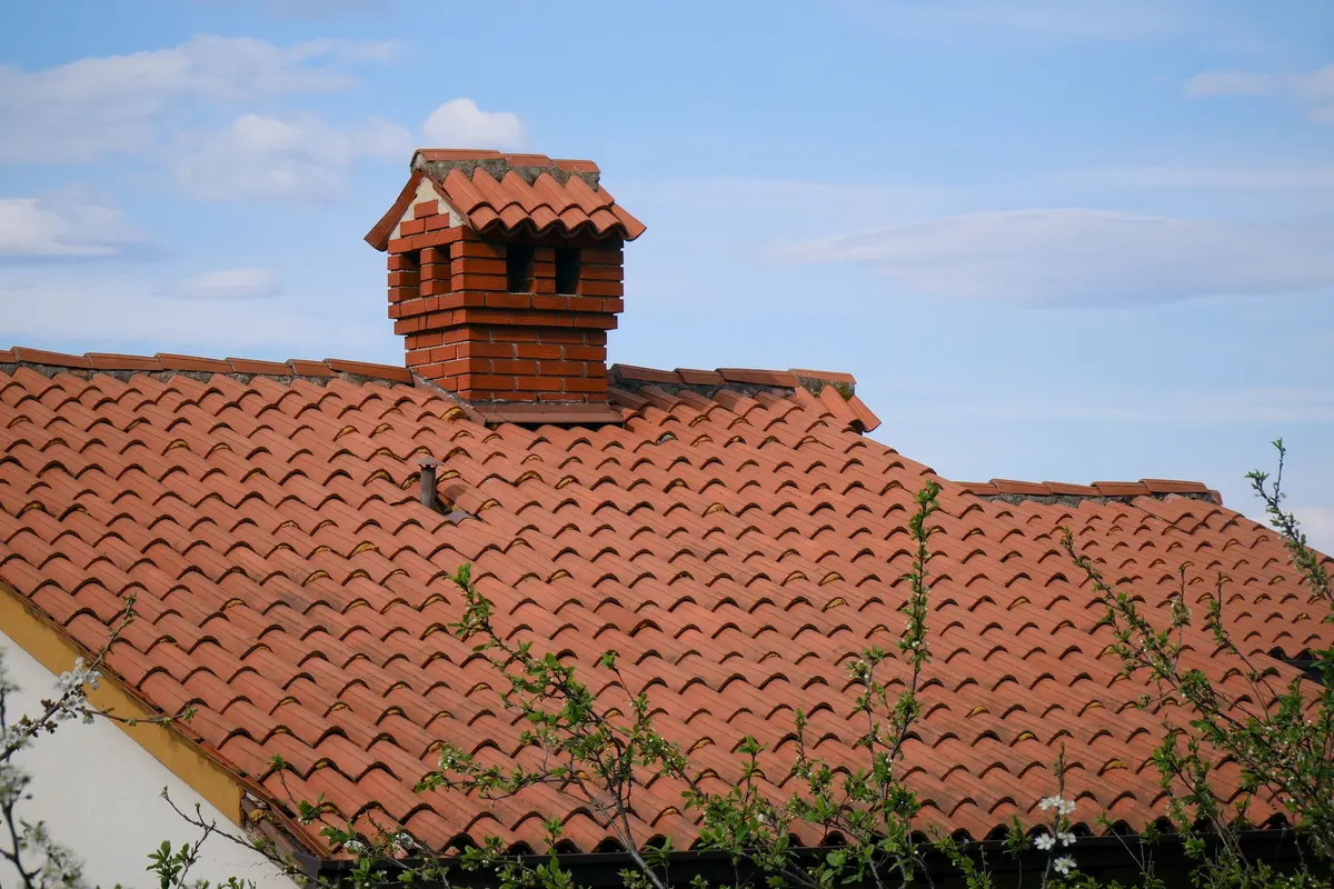 Red clay tile roof with a brick chimney on a home in Los Angeles, CA
